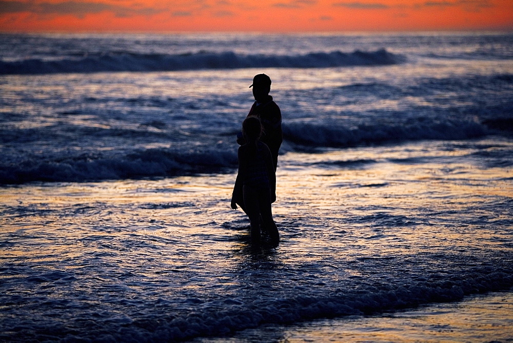 Father and his daughter standing in the water at the beach