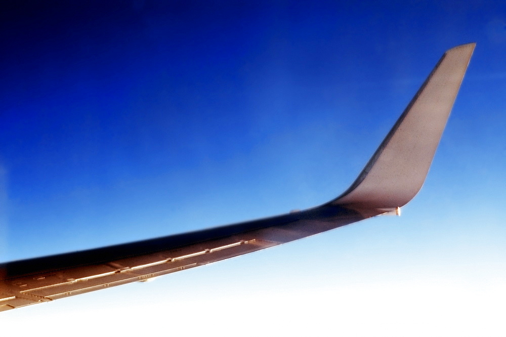 Close-up of an airplane wing against blue sky