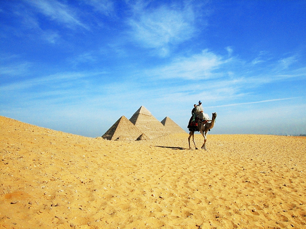 Two people on a camel in front of the pyramids, Giza Pyramids, Giza, Cairo, Egypt