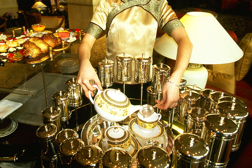 Mid section view of a waitress pouring tea in tea cups, Pudong Shangri-La, Shanghai, China