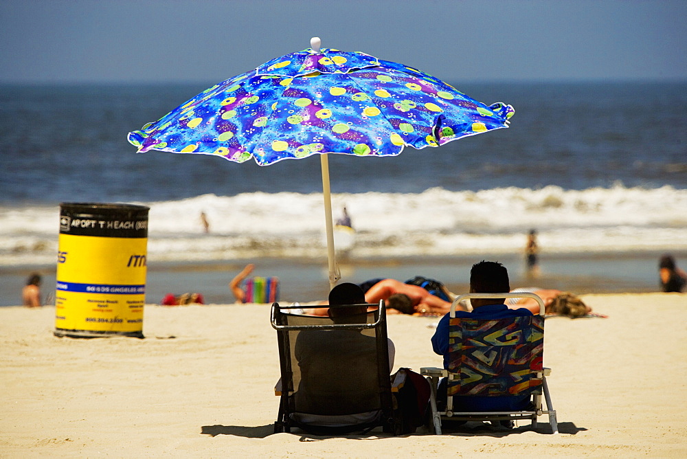 Rear view of two people sitting on the beach