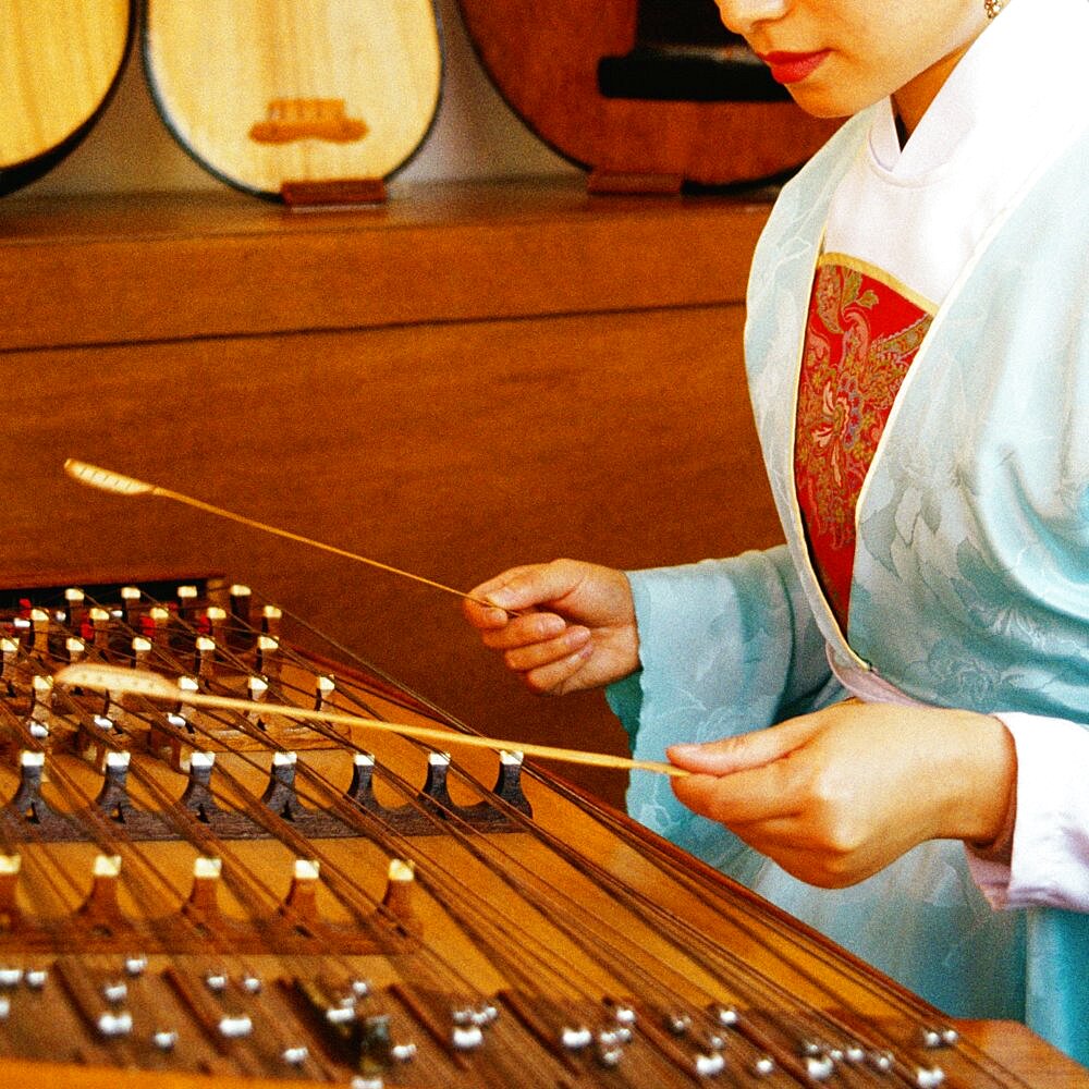 Side profile of a young woman playing dulcimer, Hong Kong, China