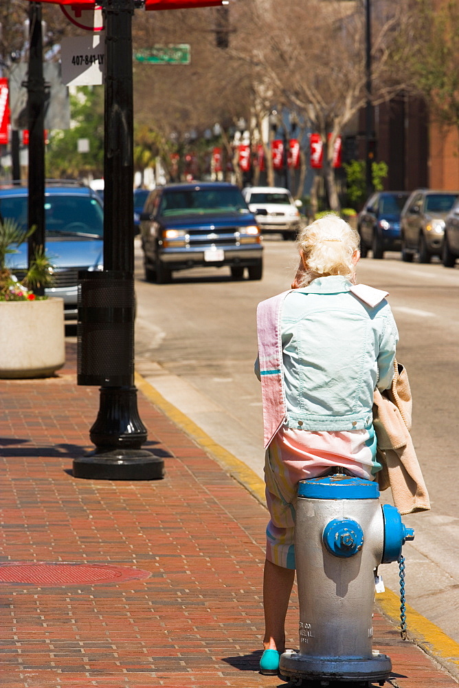 Rear view of a person sitting on a fire hydrant, Orlando, Florida, USA