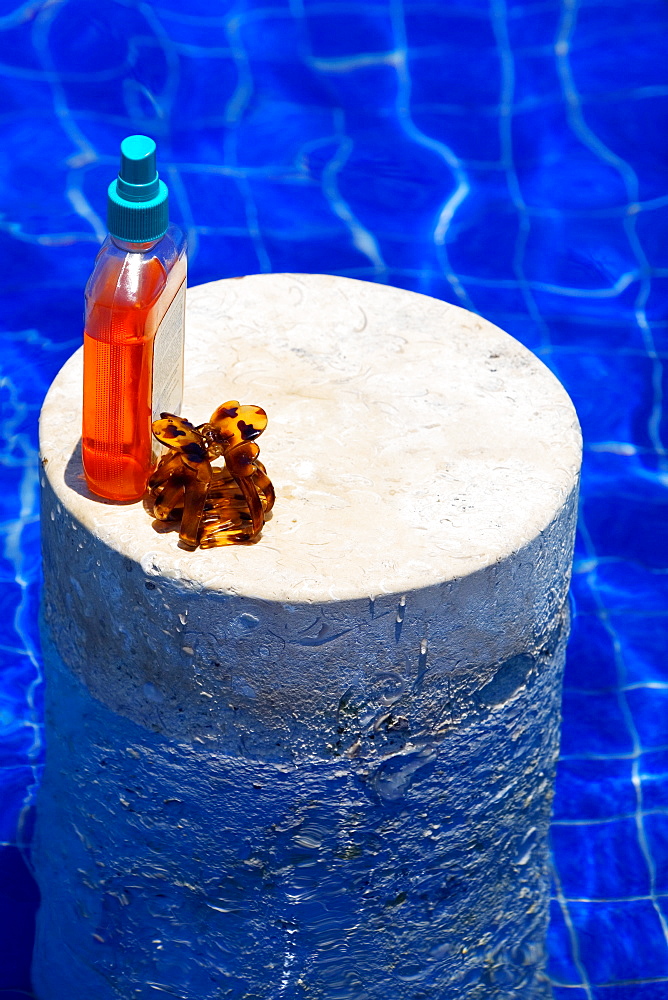 High angle view of an oil bottle and a clutcher on a column in a swimming pool, Cancun, Mexico