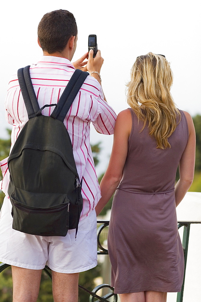 Rear view of a mid adult couple taking photographs with a mobile phone, Capri, campania, Italy