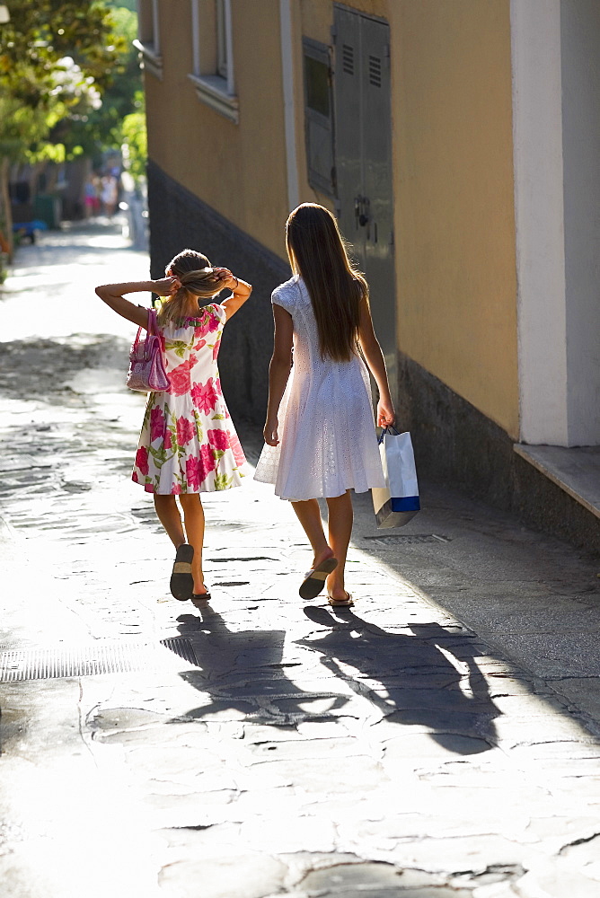 Rear view of two girls walking in a street, Capri, Campania, Italy