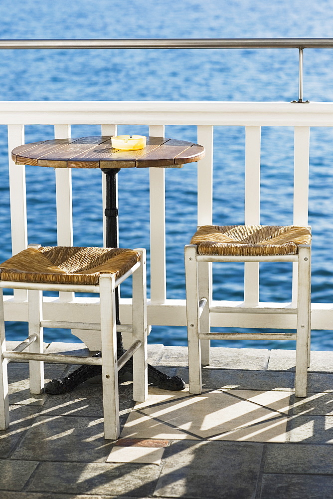 Empty table with stools near a railing in a restaurant, Mykonos, Cyclades Islands, Greece