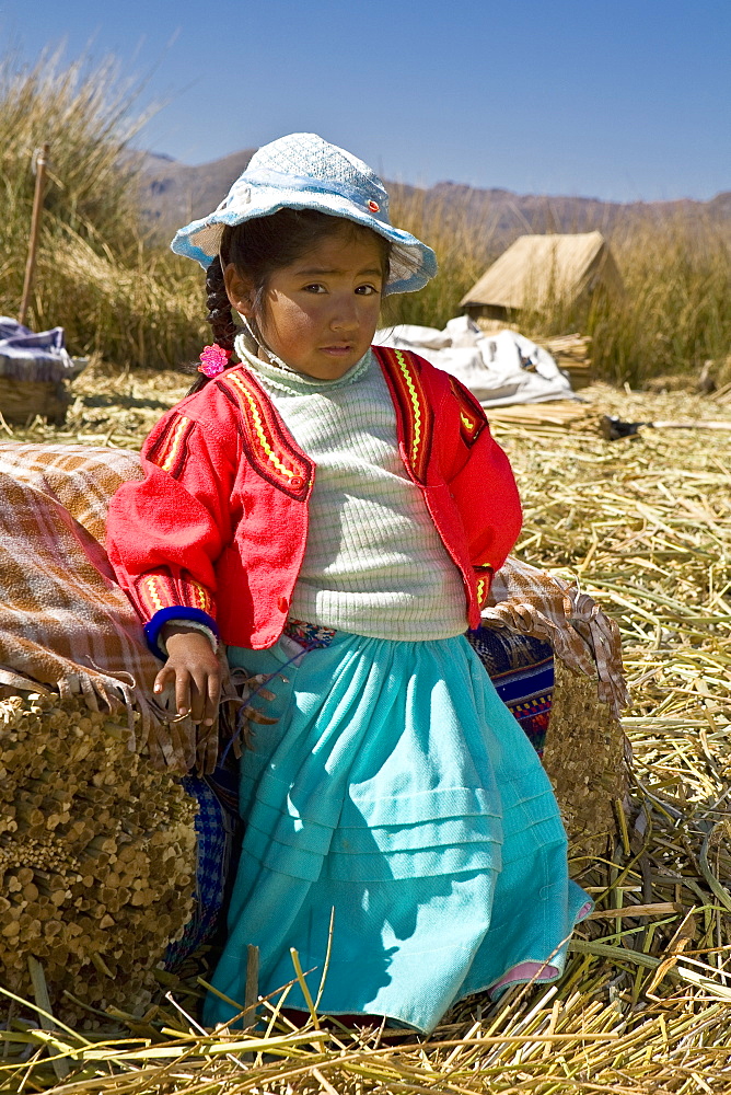 Portrait of a girl leaning against a bale of straw