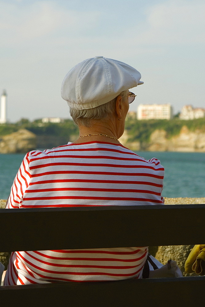 Rear view of a woman sitting on a bench, Phare De Biarritz, Baie De Biarritz, Biarritz, France