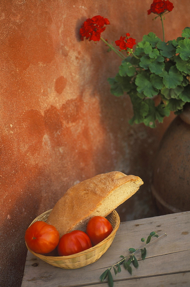 Three tomatoes and a piece of bread in a wicker basket