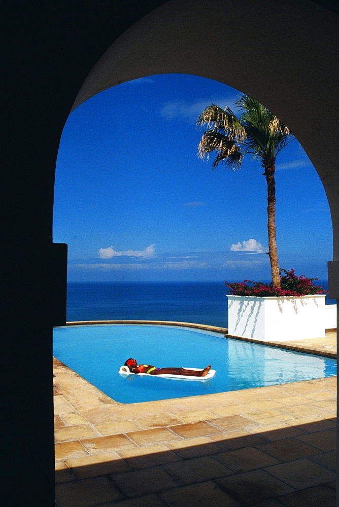 A woman is relaxing on a float in a swimming pool, Destiny Villa, Jamaica