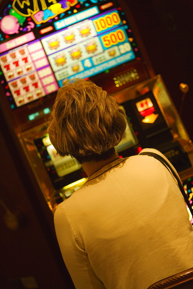 Rear view of a woman sitting in front of slot machine, Las Vegas, Nevada, USA