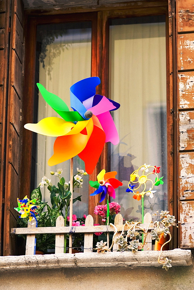 Low angle view of pinwheels with flower vases in front of a window