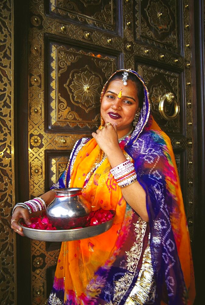 Portrait of a mid adult woman standing in front of a door and greeting, Jaipur, Rajasthan, India