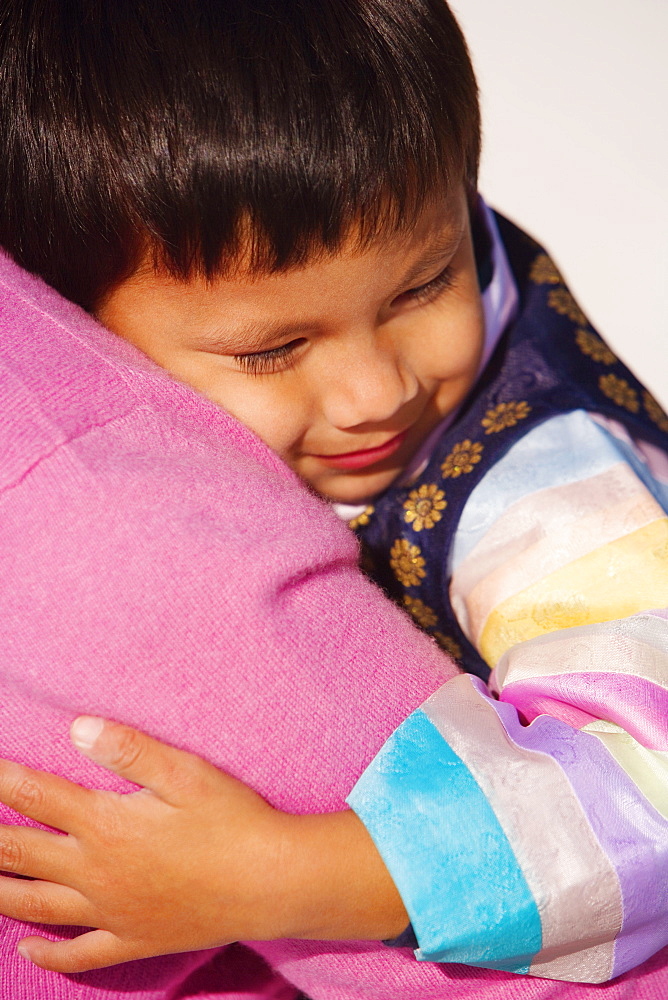 Close-up of a boy hugging his mother