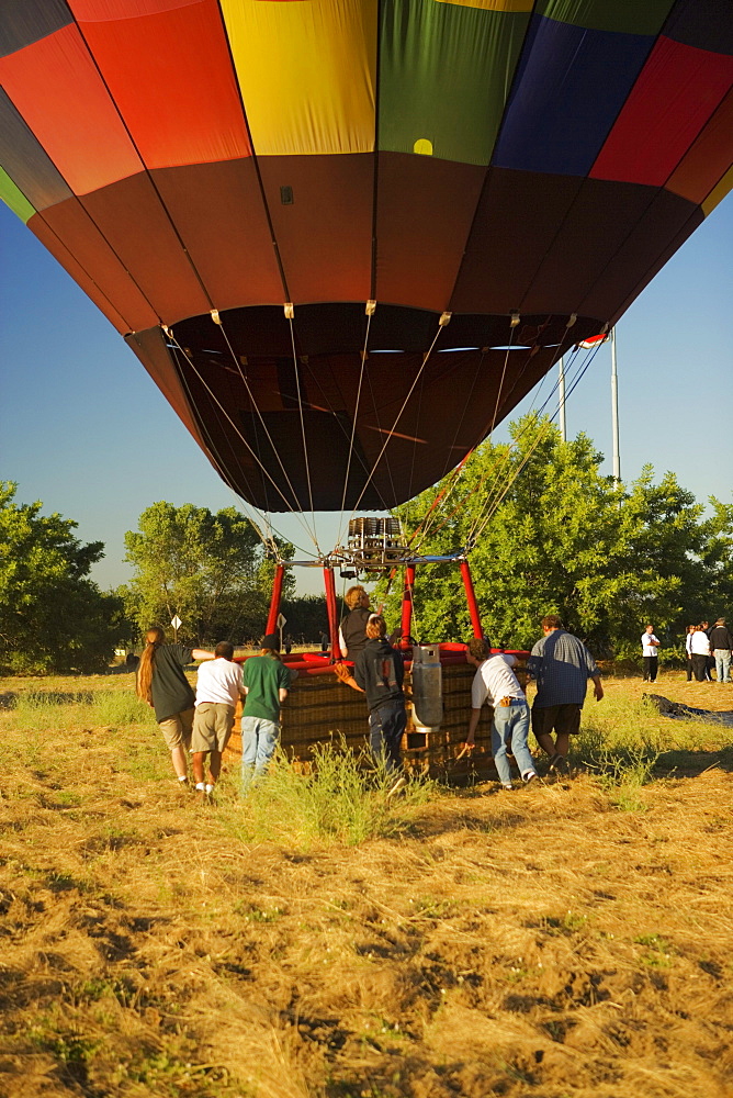 Rear view of people pulling hot air balloon