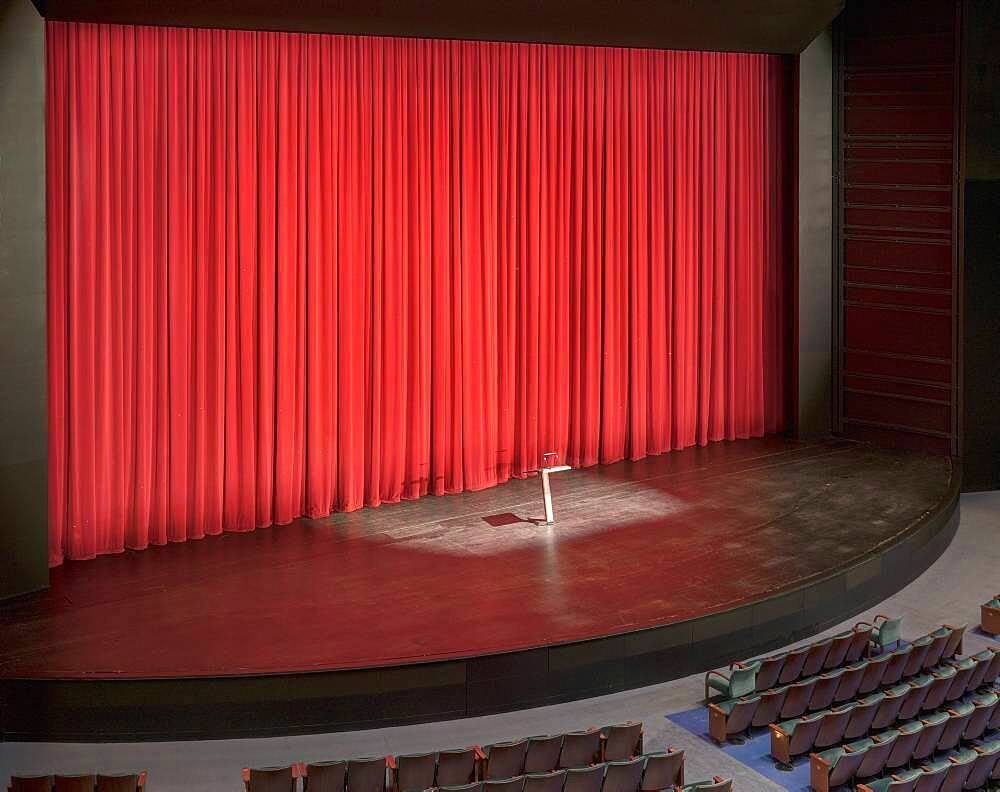 Stage with red curtains in an empty auditorium.