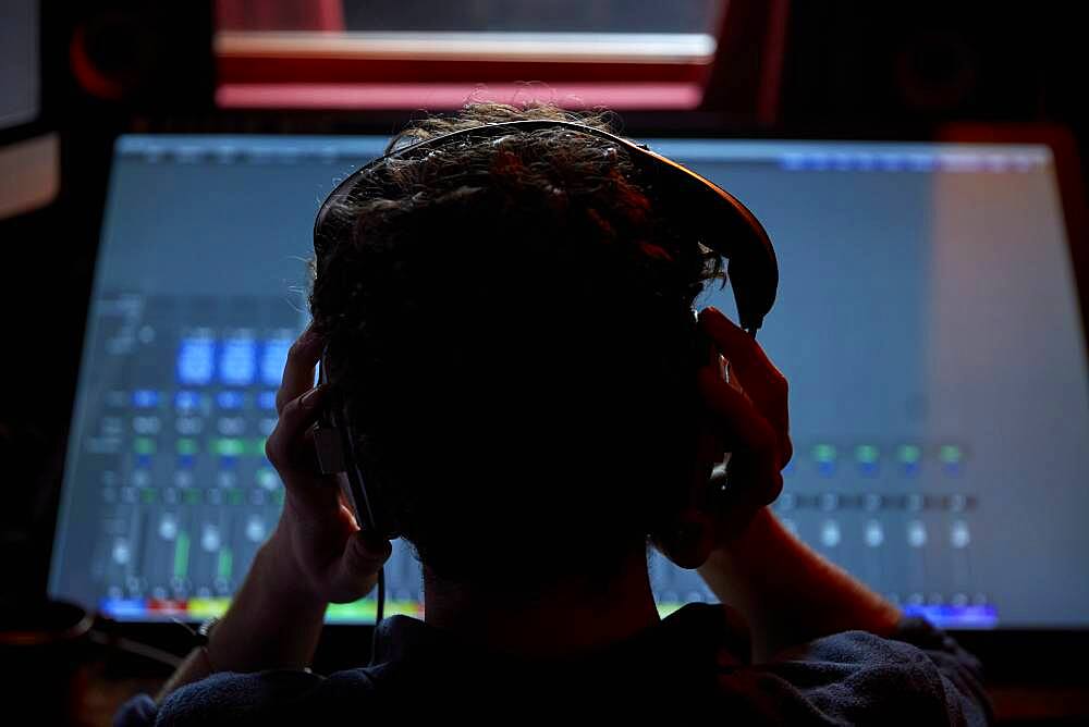 Man working in music studio, using large computer screen