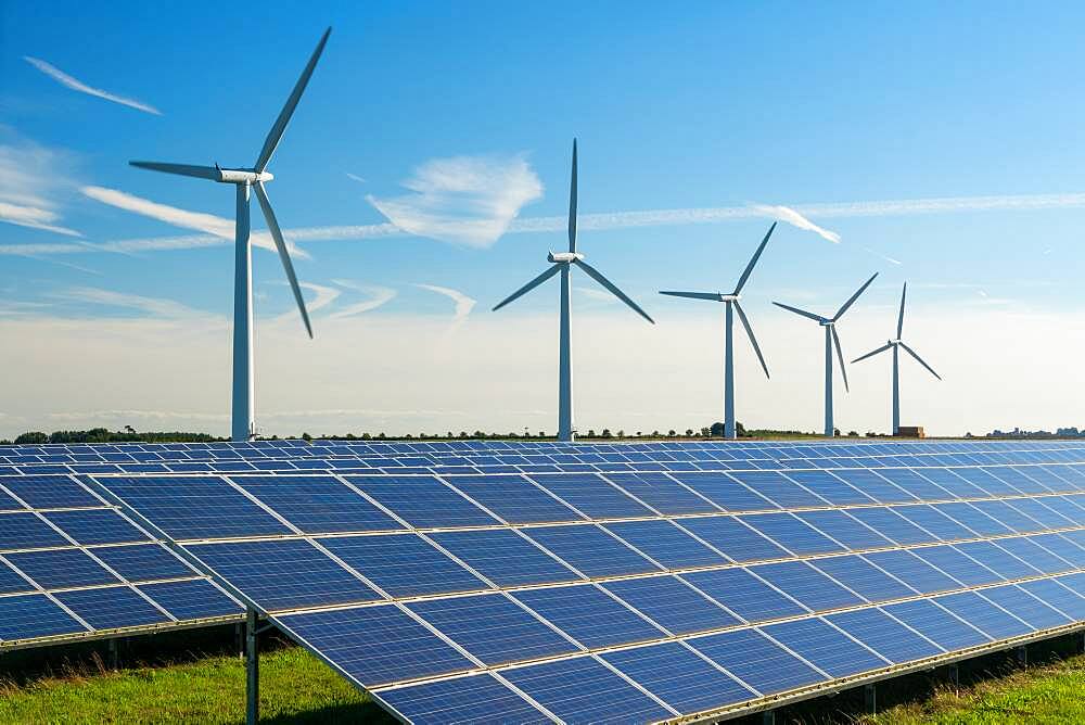 Wind turbine energy generators on wind farm, with solar panels underneath.