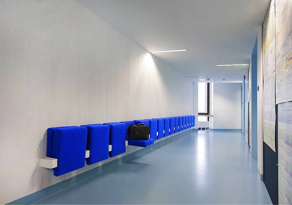 Long corridor in modern training college with blue seats.