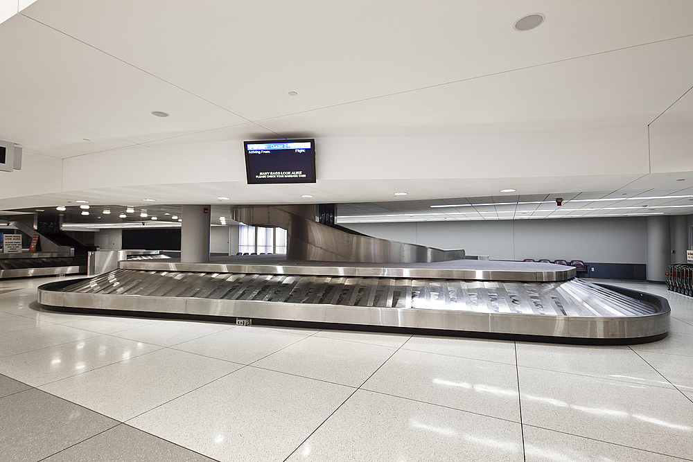 Empty airport luggage claim area, carousels and trolleys.