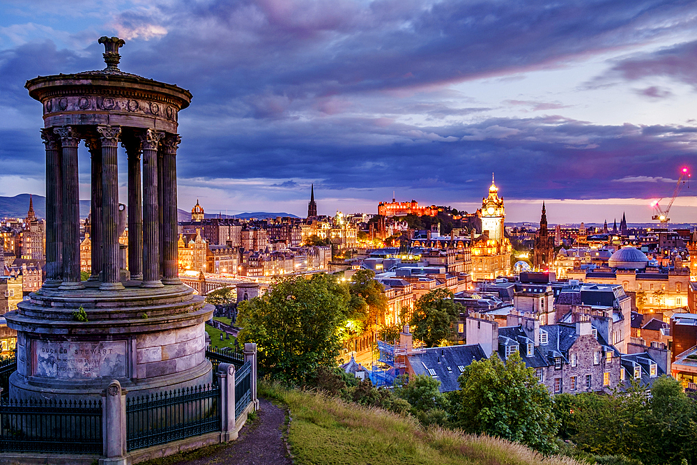 Calton Hill Folly and Edinburgh skyline lit up at dawn.