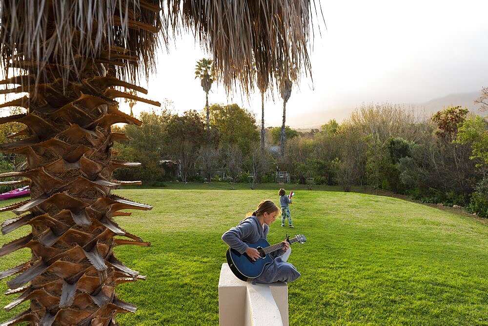 Teenage girl playing guitar and singing outdoors, Stanford, Western Cape, South Africa