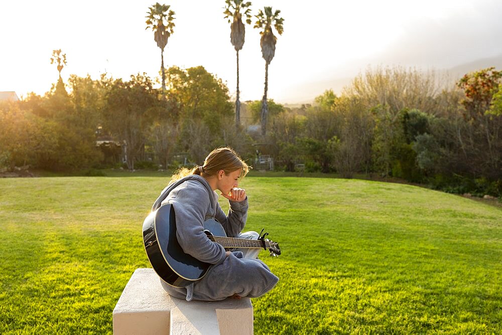 Teenage girl playing guitar and singing outdoors, Stanford, Western Cape, South Africa