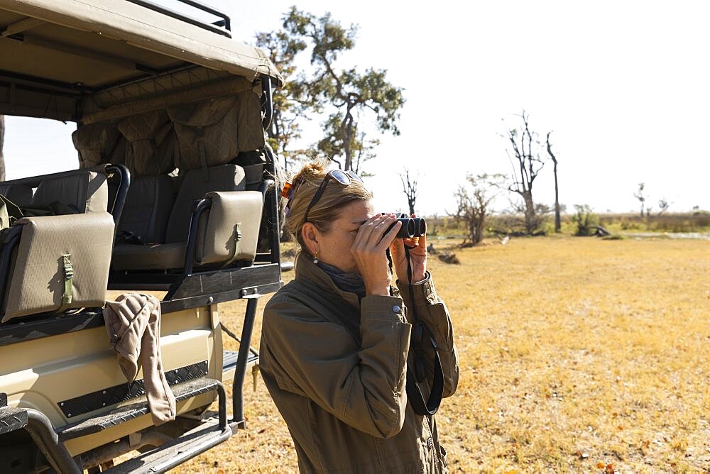 woman using binoculars,Okavango Delta, Botswana, Okavango Delta, Botswana