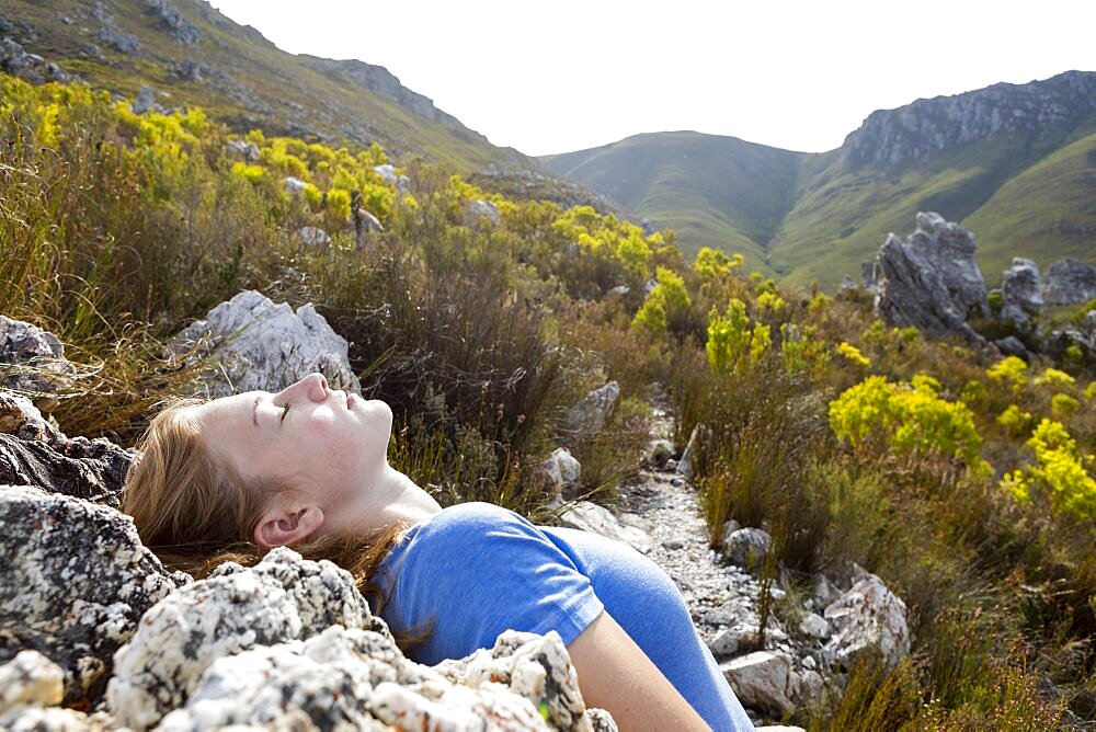 Teenage girl leaning back and resting in the sun on a nature trail path, Phillipskop Nature Reserve, Western Cape, South Africa