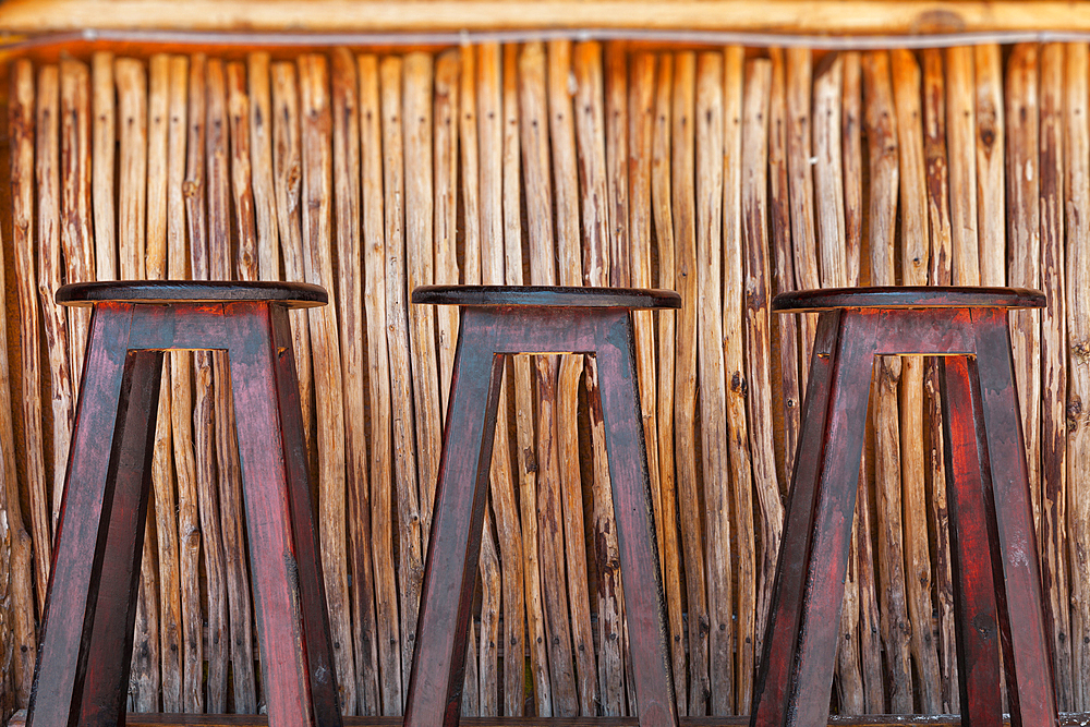 Three bar stools and bar on a beach