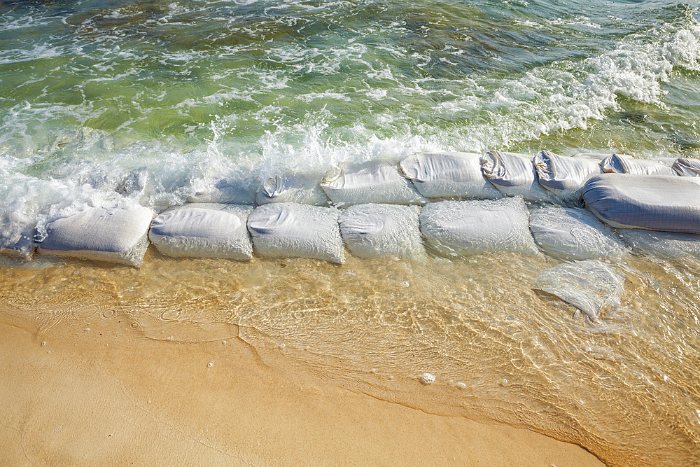 Sandbags in rows at the water's edge to prevent erosion of the beach