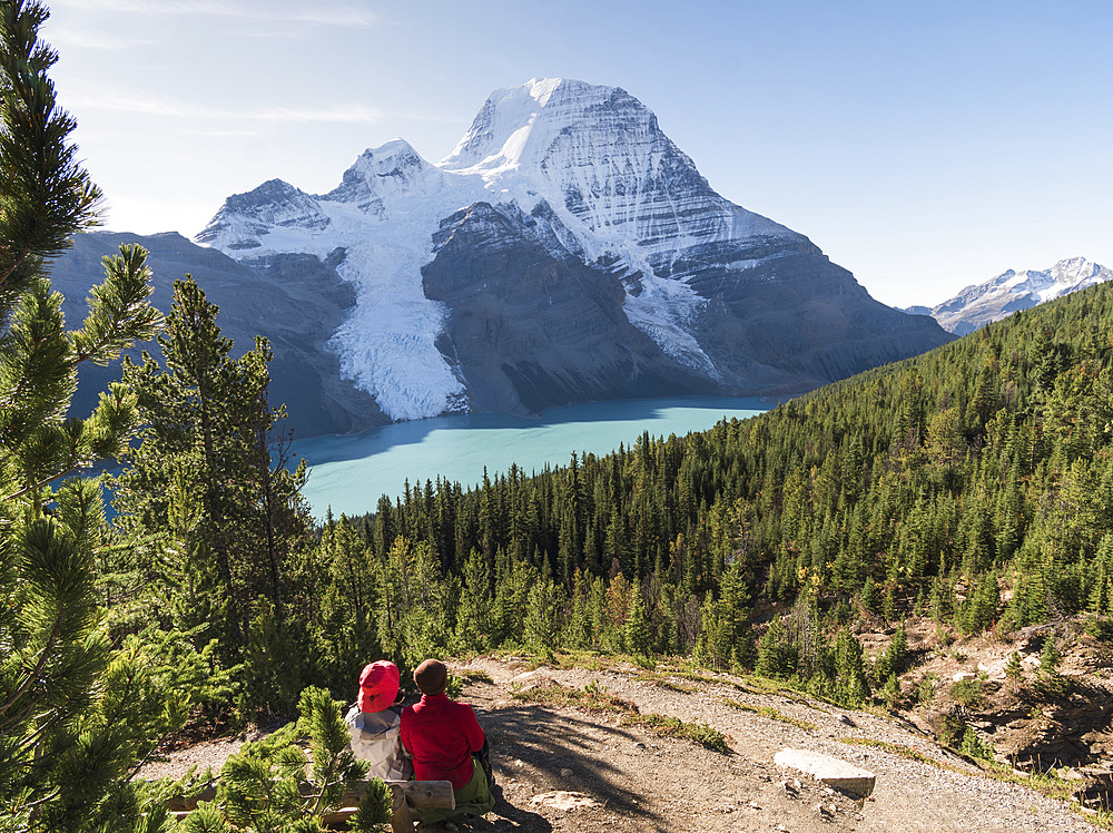 Two people resting by a hiking path, view of Mount Robson and the Rockies.