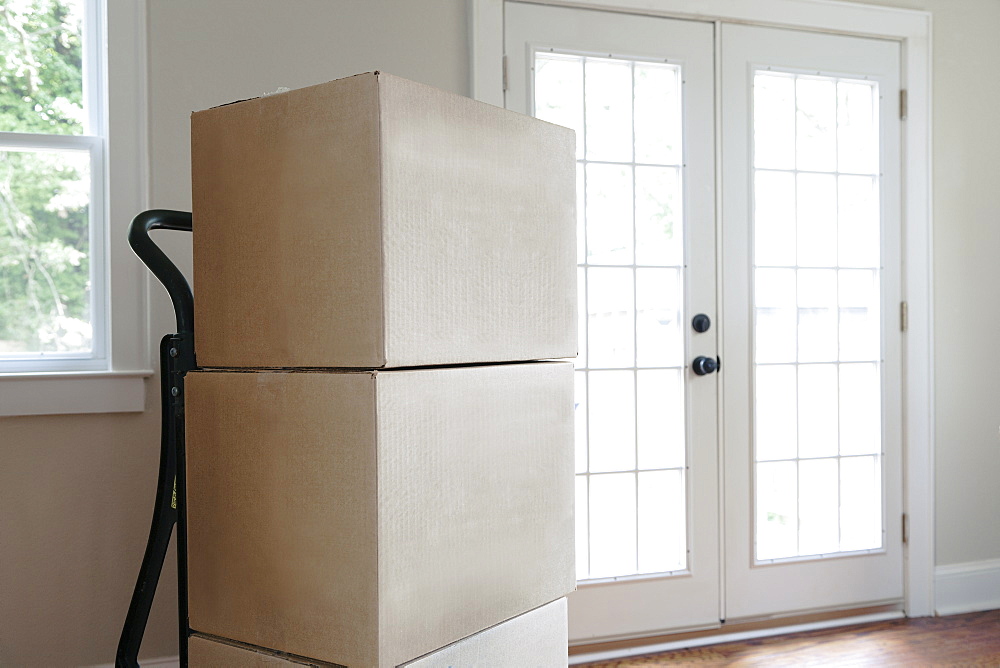 Moving house, relocation, cardboard boxes piled up in an empty house.