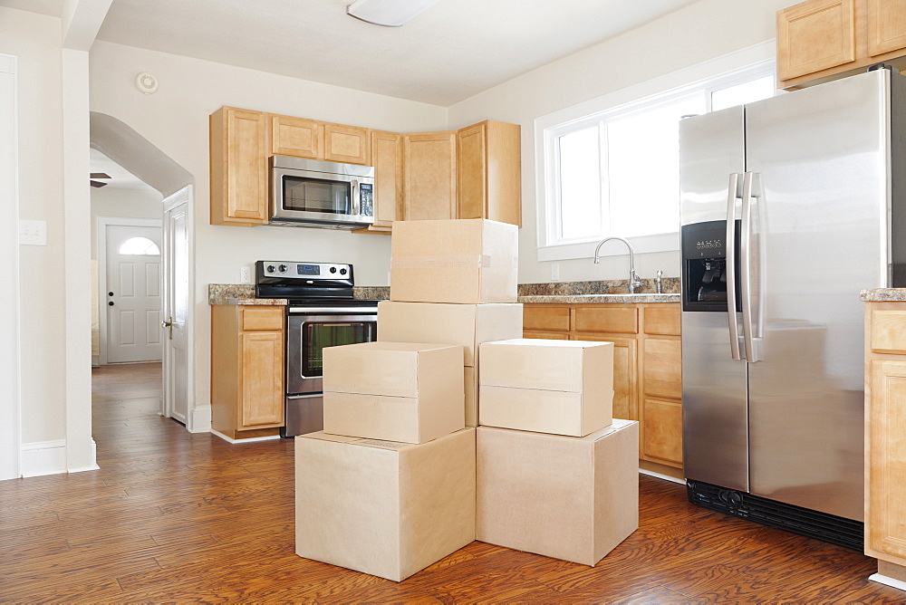 Moving house, relocation, cardboard boxes piled up in a house fitted kitchen