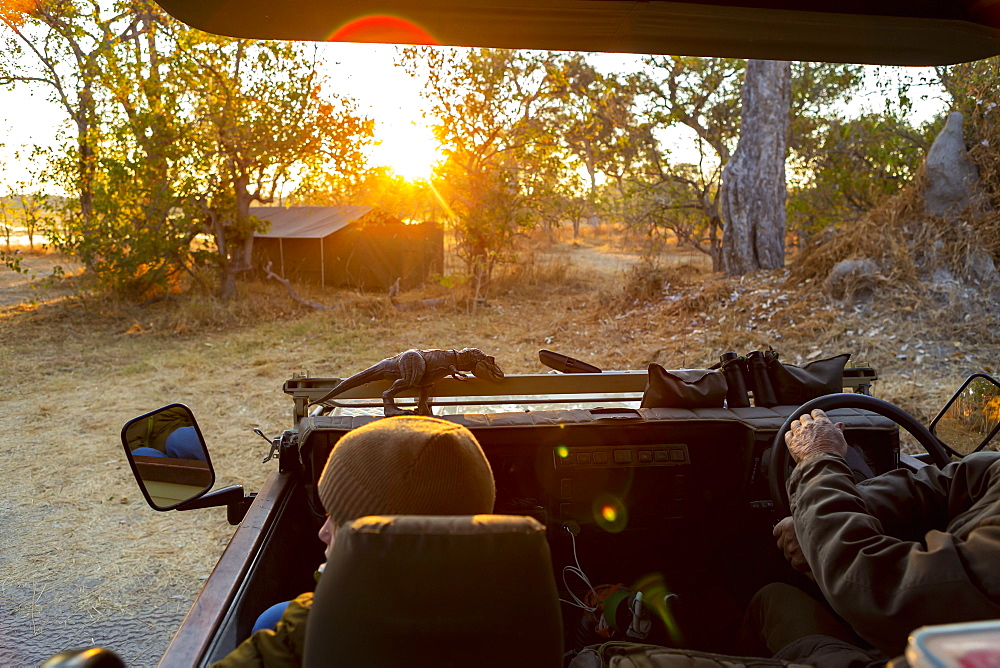 A safari jeep, view of the dirt road ahead at sunrise, lens flare, Okavango Delta, Botswana