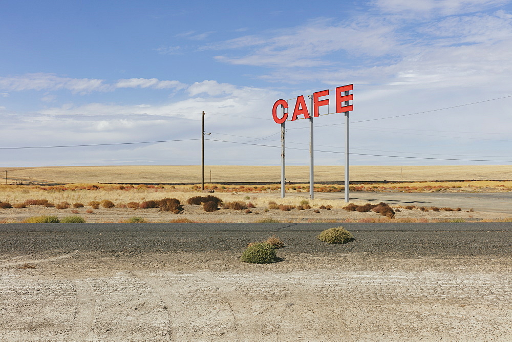 Large CAFE sign over rural farmland.