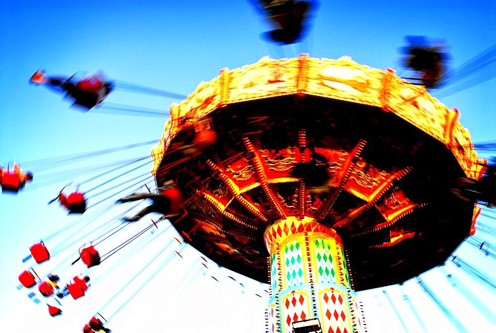 People riding on a chair swing ride or swing carousel seen from below.