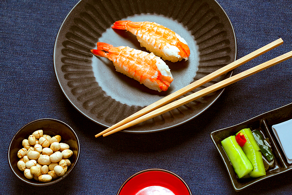 Prawns and rice on a blue dish with chopsticks.