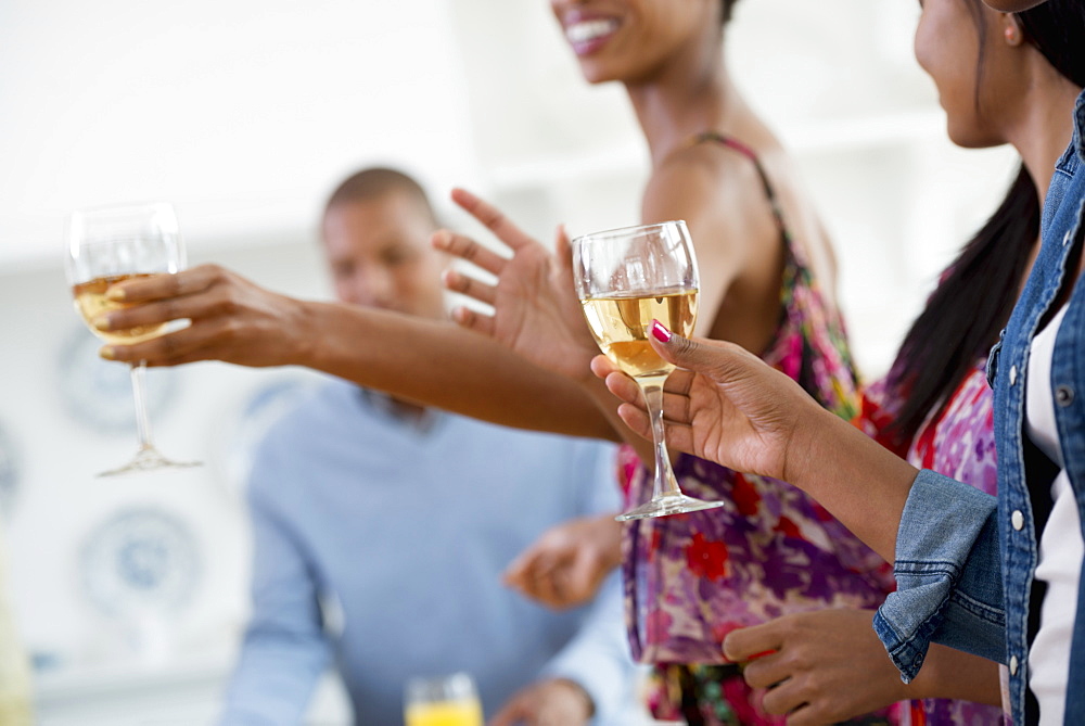 A group of people gathering for a party and a meal. An informal office party or networking social event. People handing plates of food across a buffet table.