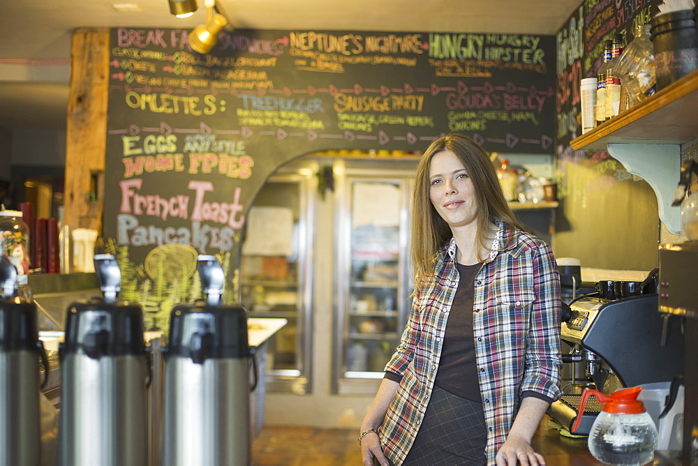 A coffee shop and cafe in High Falls called The Last Bite. A woman leaning on the counter, by the coffee machine, New York, USA