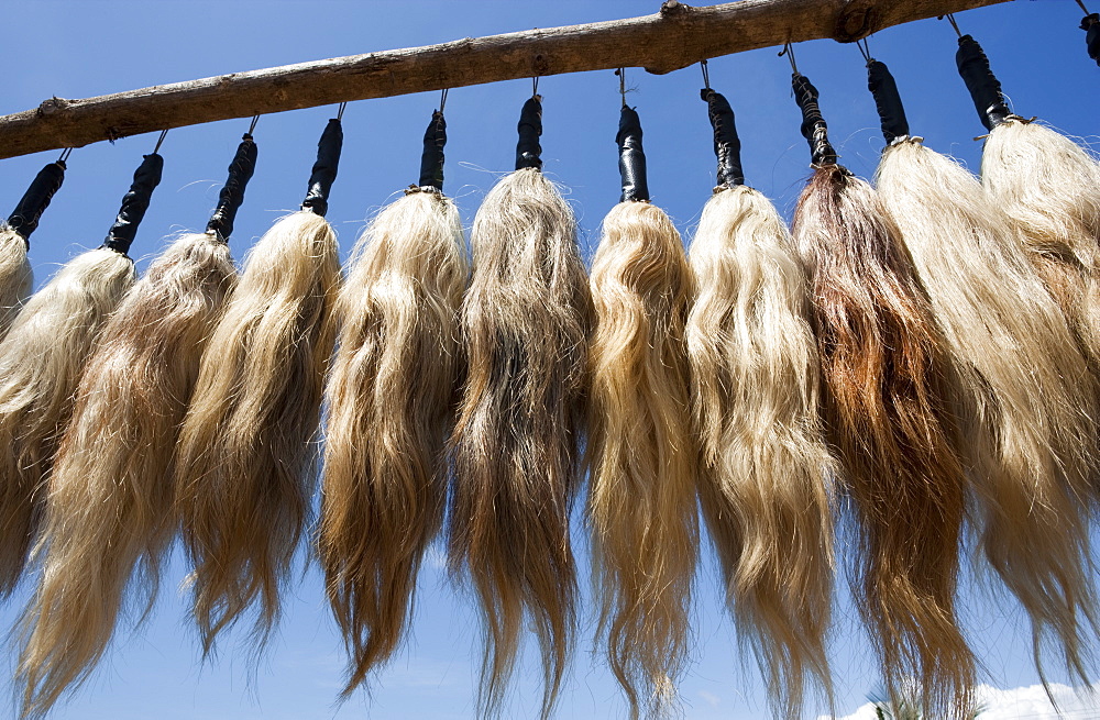 Plumes of human hair hanging from a frame against a blue sky, Togo, Africa