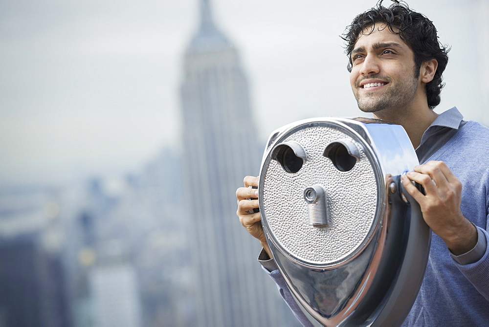 New York City. An observation deck overlooking the Empire State Building. A young man looking through a telescope over the city, New York city, USA