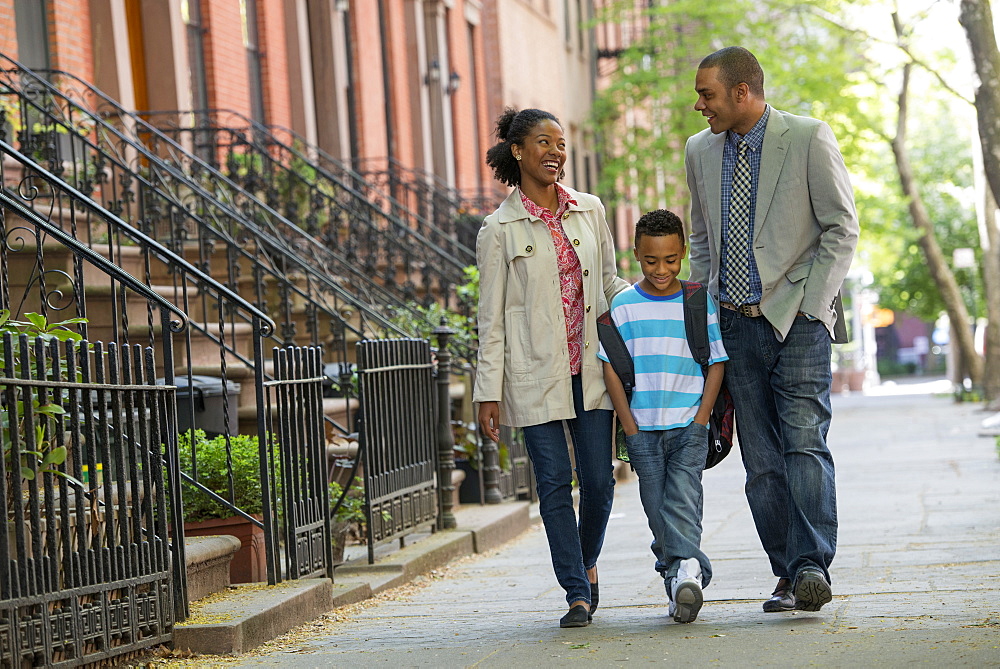 A family outdoors in the city. Two parents and a young boy walking together. 