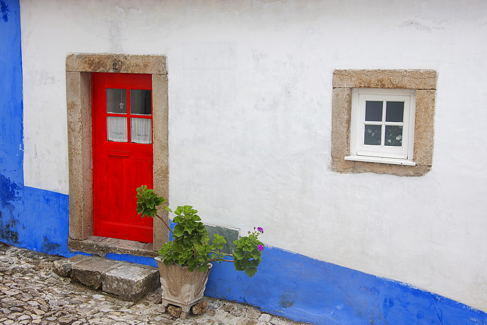 A red painted door of an old house in a street in Sonega, Sonega, Portugal