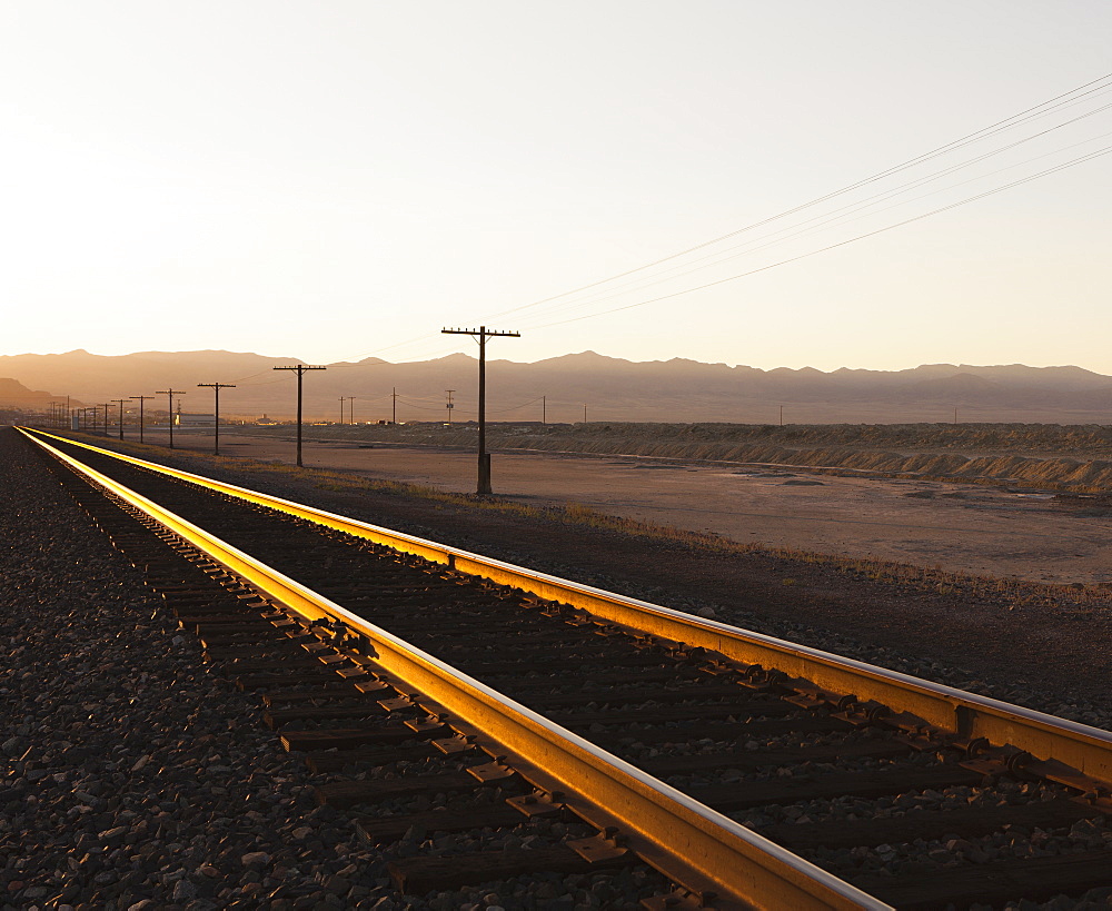 Railroad tracks extending across the flat Utah desert landscape, at dusk, Tooele County, Utah, USA