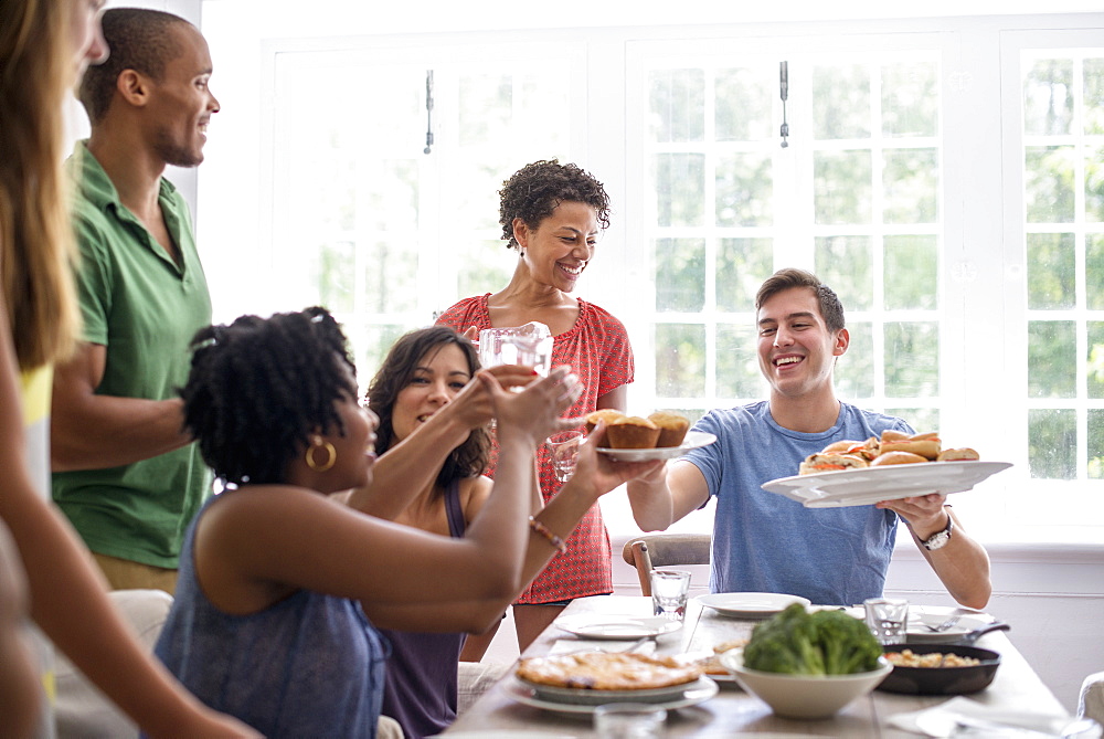 A family gathering, men, women and children around a dining table sharing a meal.