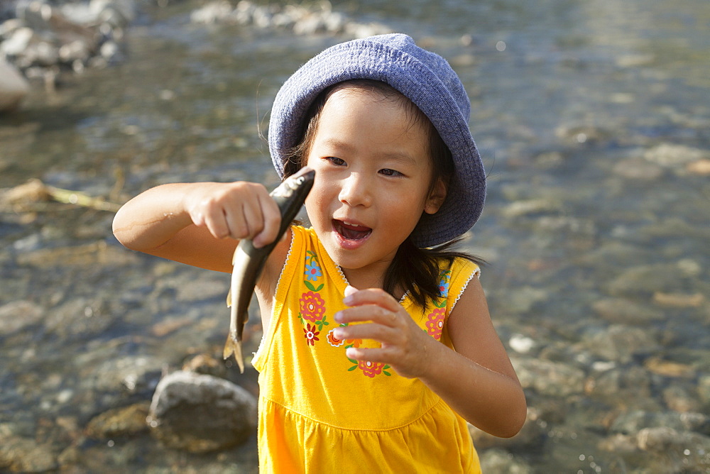 Young girl wearing a summer hat, holding a fish, Kyoto, Honshu Island, Japan