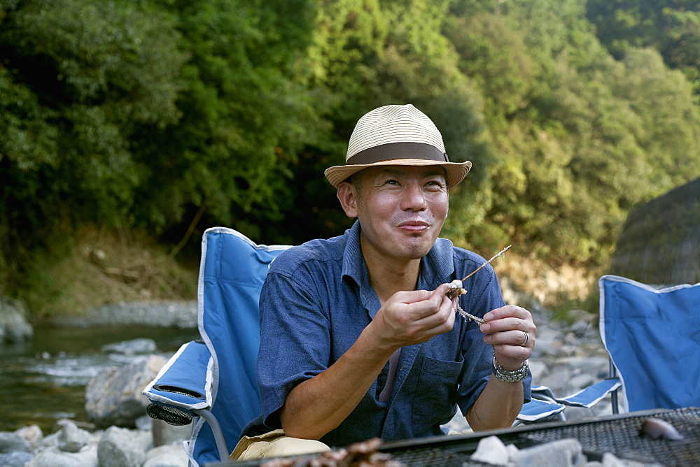 Man eating a grilled fish at a picnic, Kyoto, Honshu Island, Japan