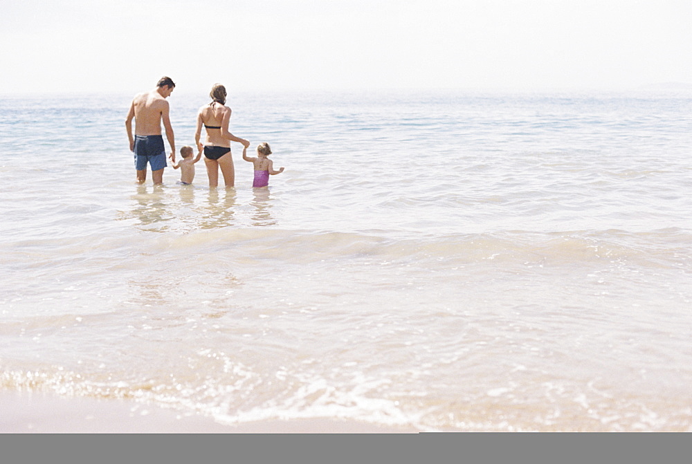 Couple with their son and daughter, A family standing in shallow water off the beach.